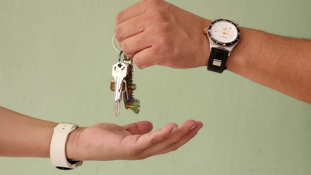 Một bàn tay trao chùm chìa khóa cho bàn tay đang đón nhận