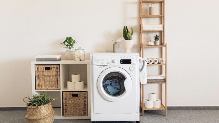 Máy giặt cửa trước và kệ đồ trong góc giặt sáng màu