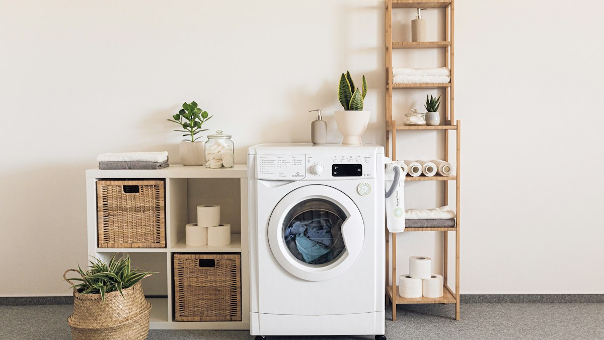 Máy giặt cửa trước và kệ đồ trong góc giặt sáng màu