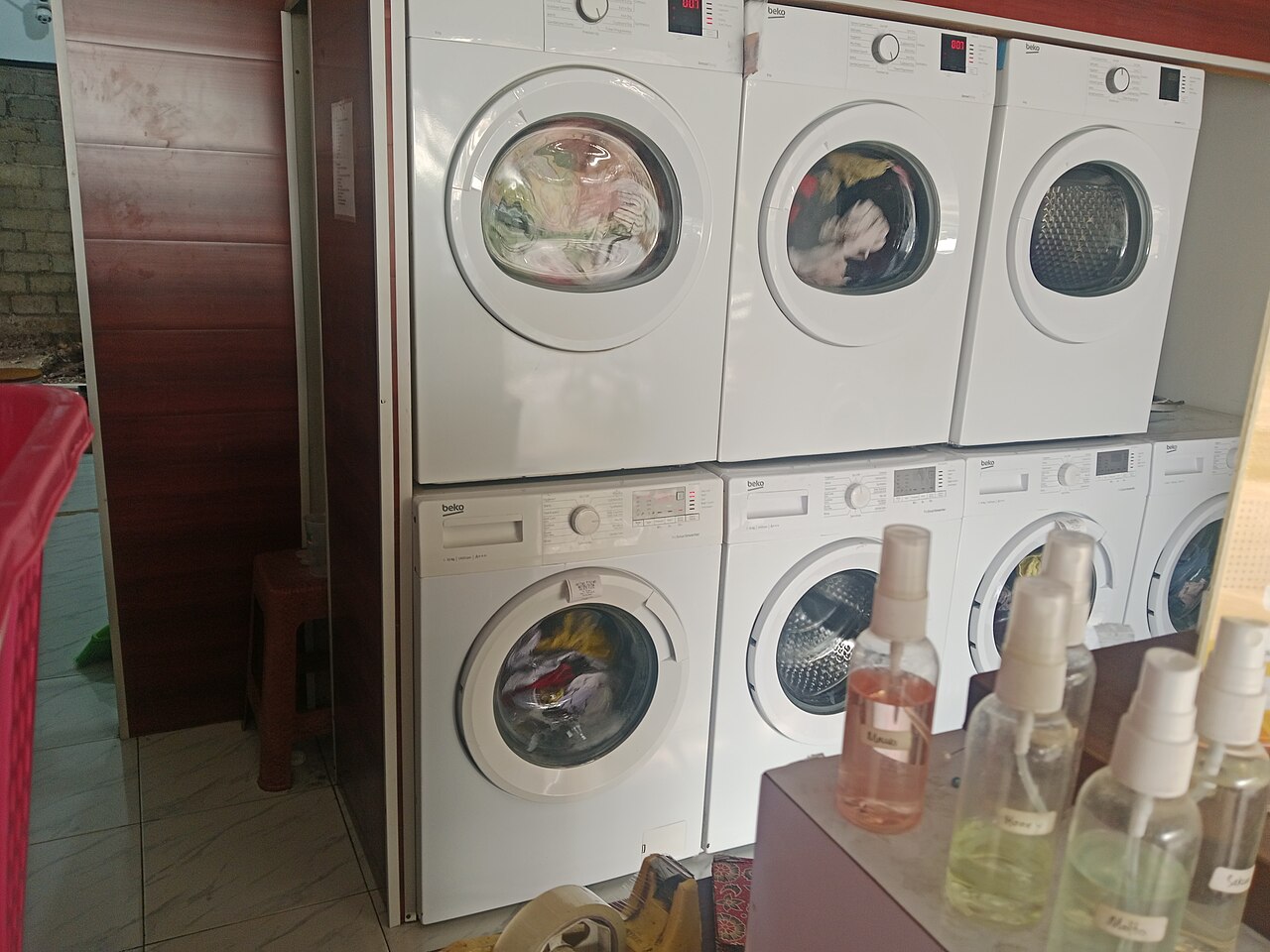 Dãy máy giặt trong một tiệm giặt, ảnh minh họa chủ đề tiếp nhận và tổ chức vật tư tại cơ sở giặt ủi